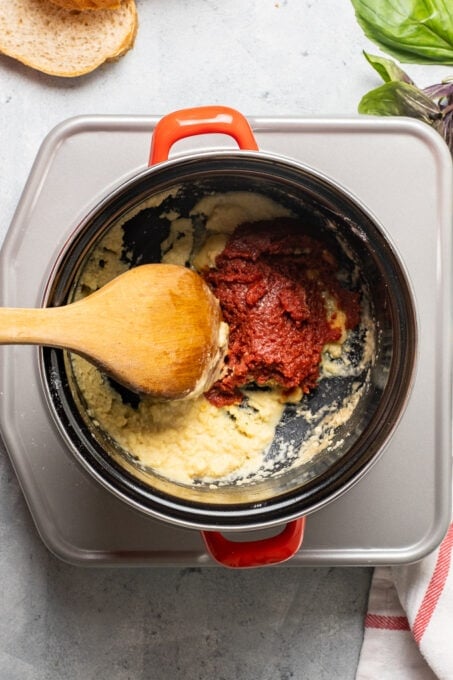 Adding tomato paste to the roux in a pot.