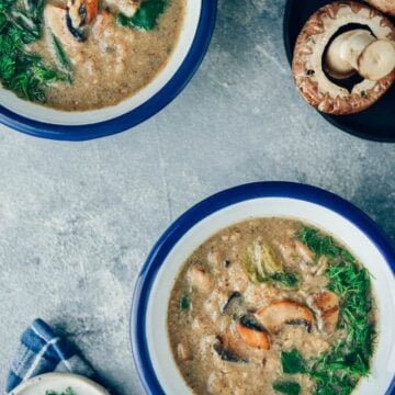 Vegan cream of mushroom soup in bowls and mushrooms accompany.
