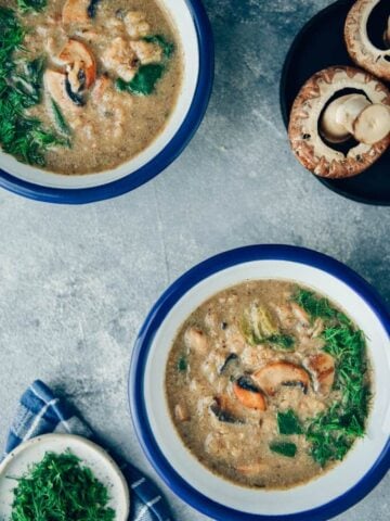 Vegan cream of mushroom soup in bowls and mushrooms accompany.