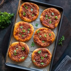 Freshly baked individual portions of Turkish biberli ekmek arranged in a baking pan.