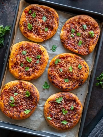 Freshly baked individual portions of Turkish biberli ekmek arranged in a baking pan.