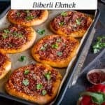 Turkish style flat breads topped with a spicy pepper mixture on a baking sheet.