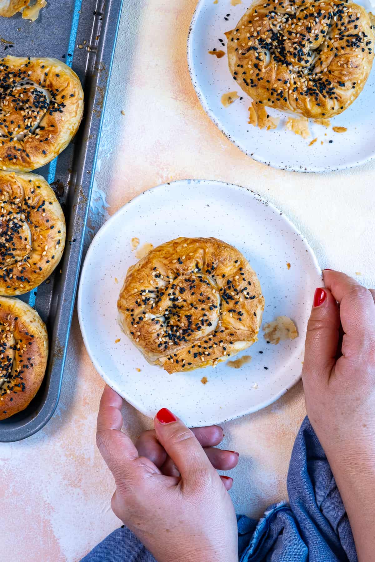 Hands holding a plate with a roll of Turkish borek.