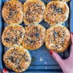 Turkish borek rolls on a baking sheet and a hand is taking one.