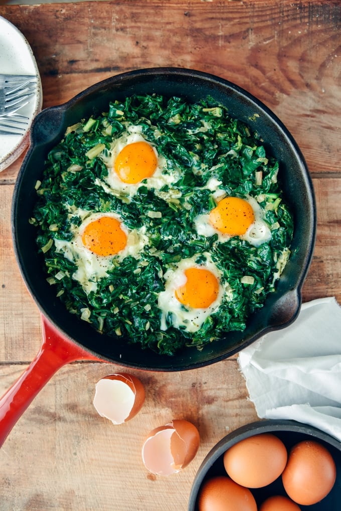 Fried Eggs with Spinach is an easy dish you can make in one pan. It is packed with great flavors and nutritious foods. Makes a delicious lunch or dinner that is ready in no time! #eggs #spinach #eggswithspinach Eggs with spinach in a cast iron skiller