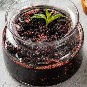 Mulberry jam in a jar garnished with fresh mint.