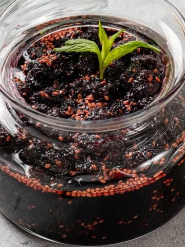Mulberry jam in a jar garnished with fresh mint.