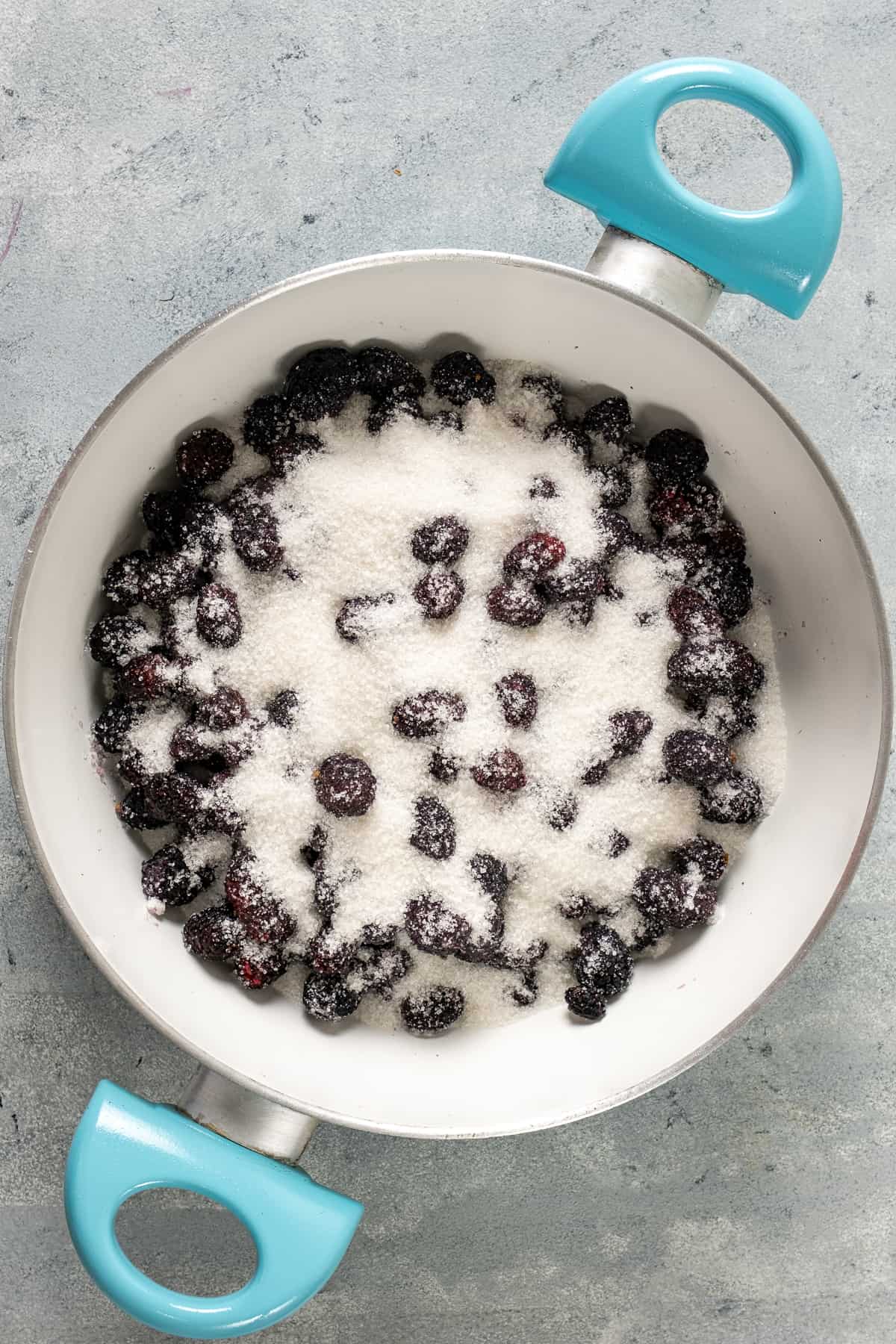 Mulberries coated with granulated sugar in a white pan.