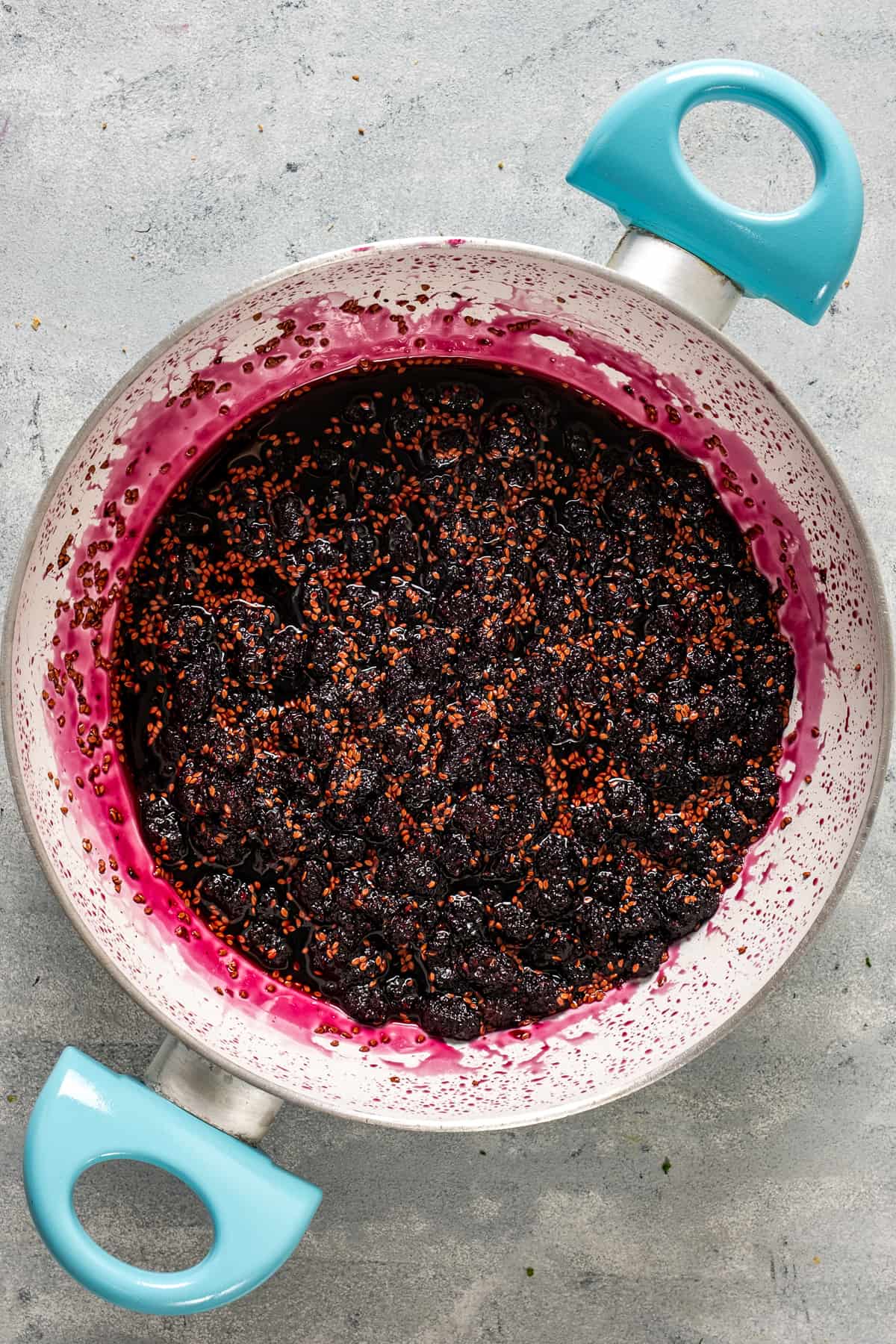 Mulberry jam simmering in a white pan.