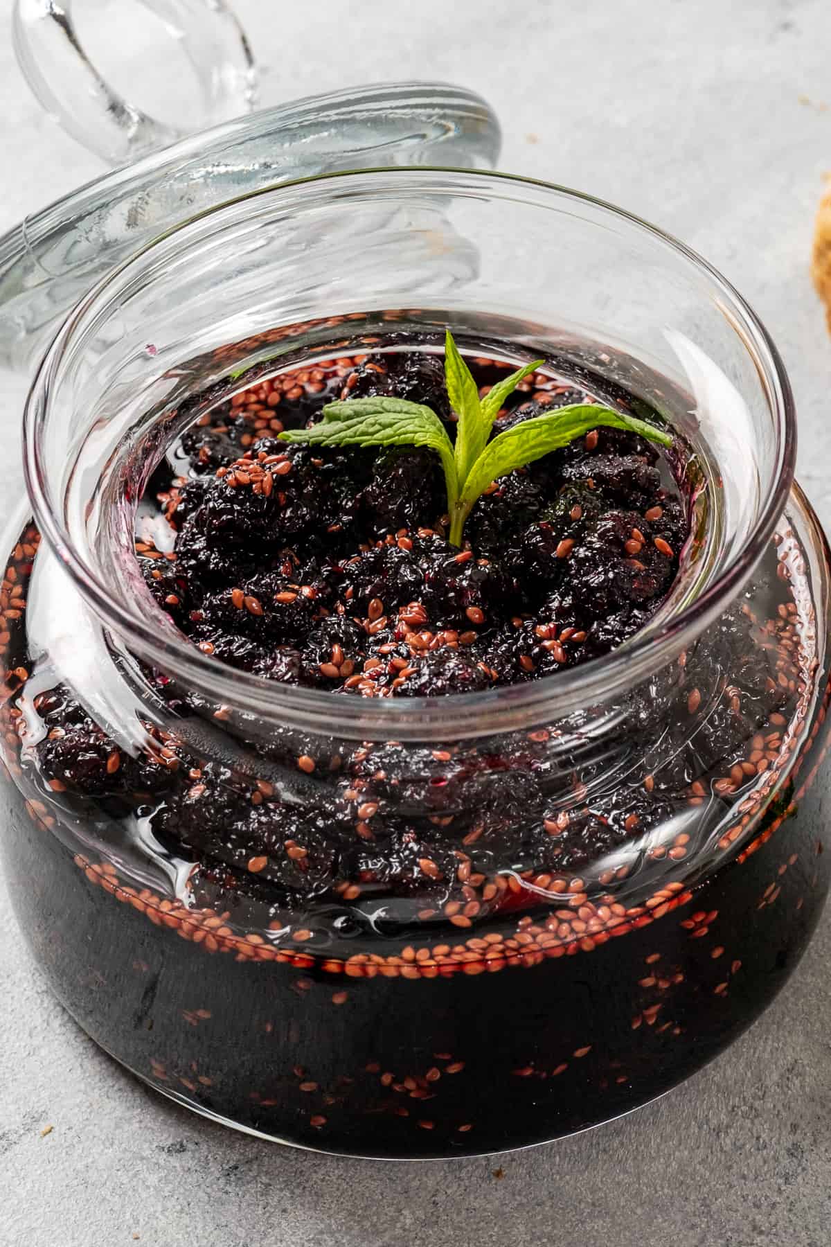 Mulberry jam in a jar, garnished with fresh mint.
