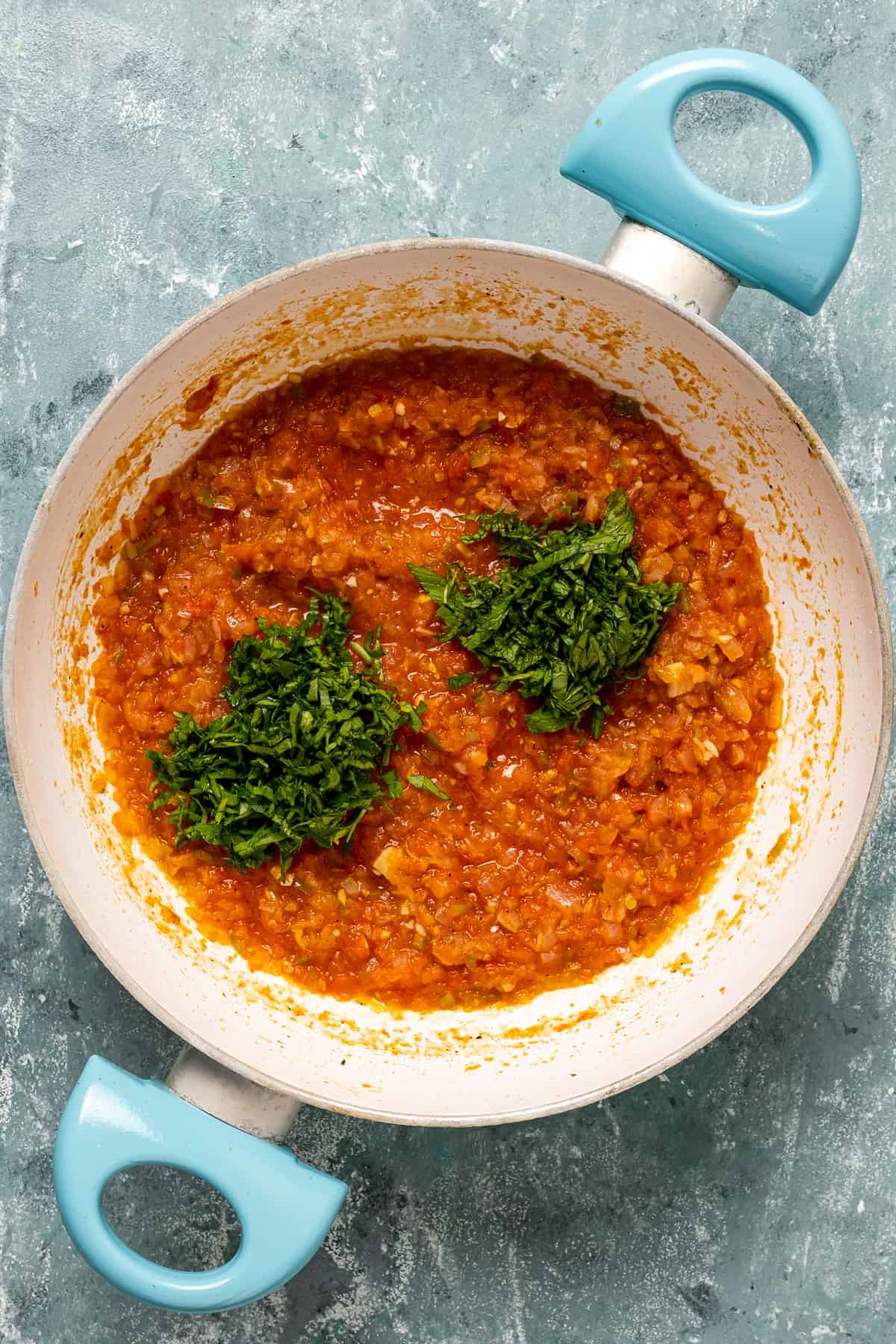 Imam bayildi filling with tomatoes, onions and herbs in a white pan.