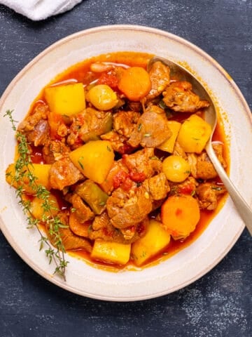 Lamb stew with potatoes and carrots in a large bowl and a spoon in it.