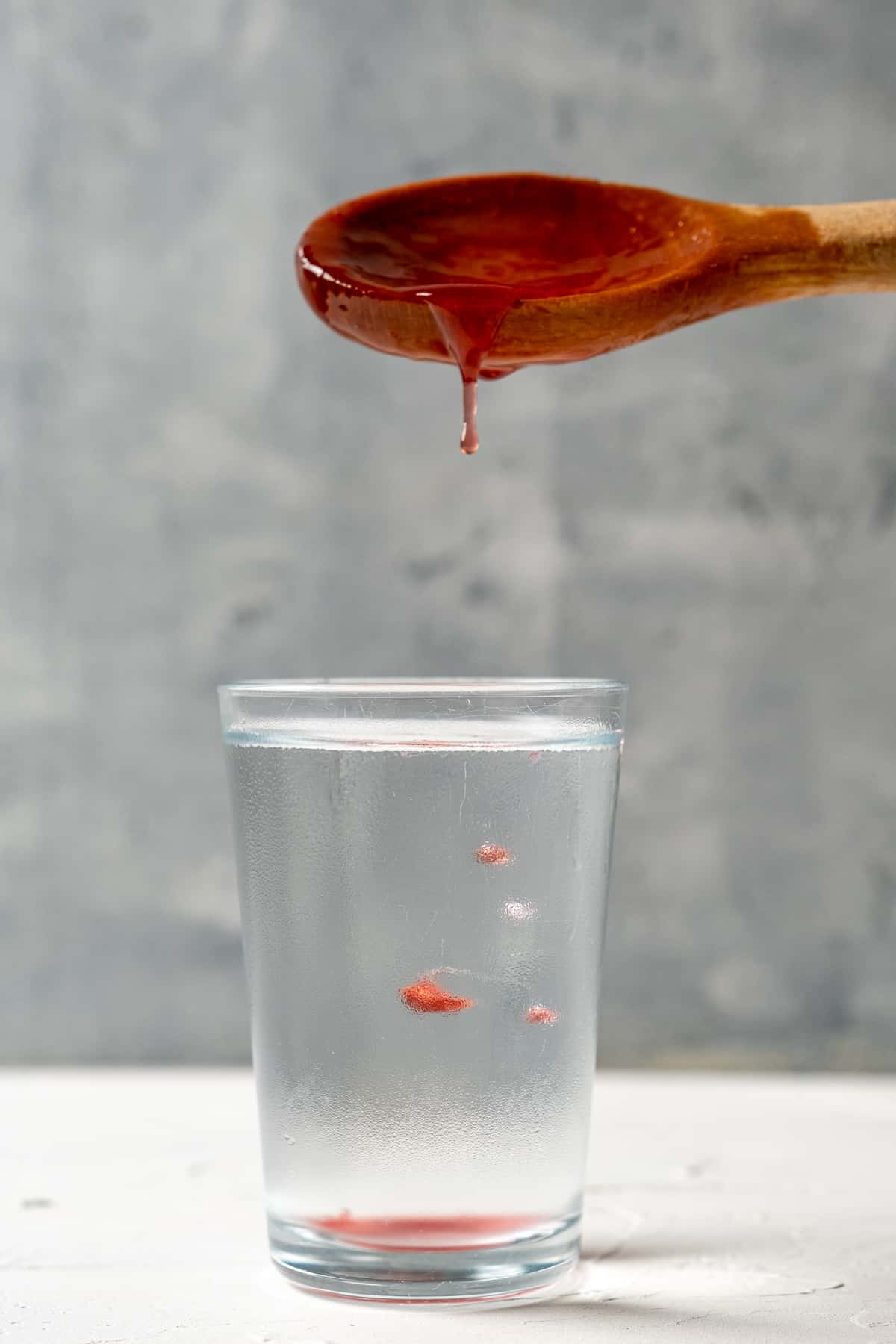 Dropping a little jam into a glass of cold water to test the consistency of the plum jam.