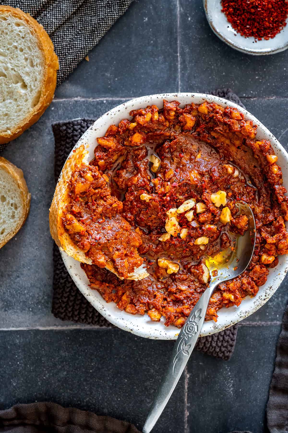 Slice of bread topped with homemade acuka, a Turkish breakfast spread made with walnuts, tomato paste, pepper paste, garlic and spices, served with olive oil and pul biber.