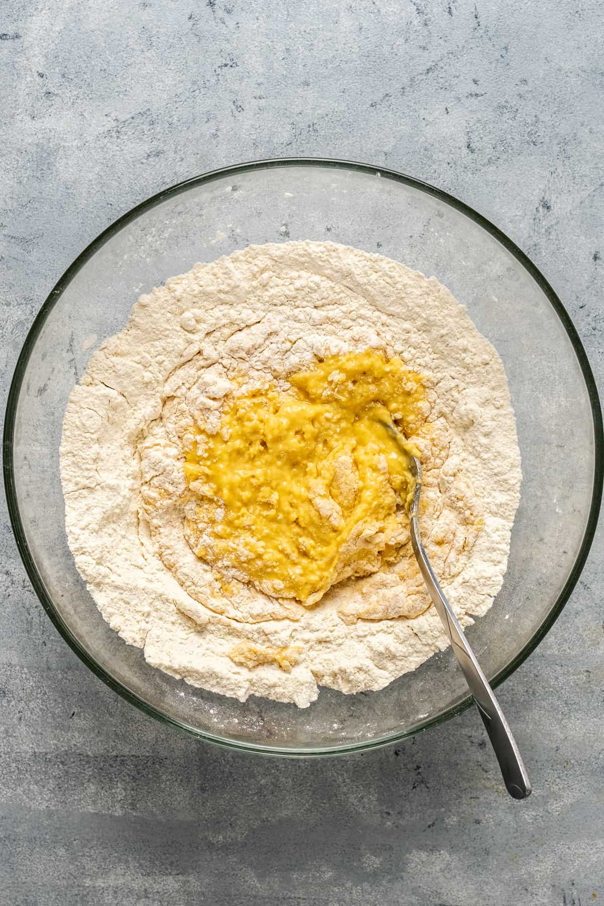 Flour and egg mixture in a glass mixing bowl and a fork inside it.