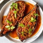 Turkish stuffed eggplants karniyarik garnished with parsley on a white plate.