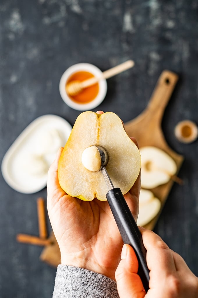 Woman hands removing the core of a pear with a melon baller.