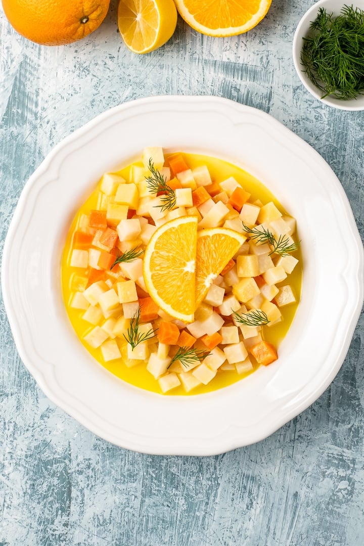 Turkish style citrus flavored celeriac dish in a round white dish topped with orange wedges.