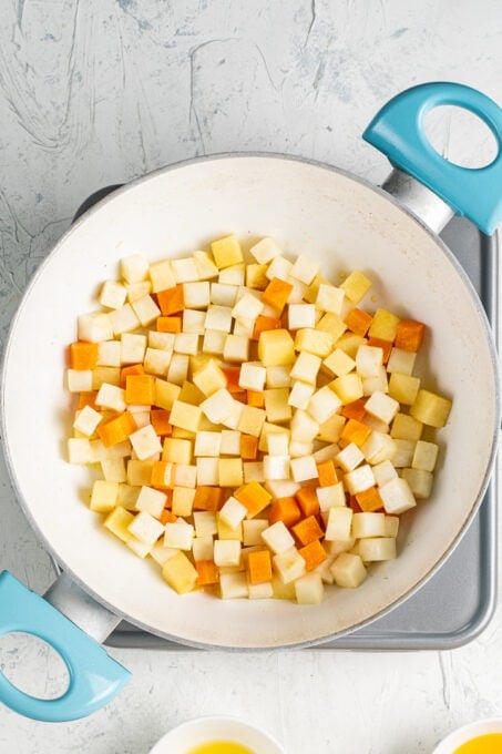 Diced celery root, quince and carrot in a white pan.