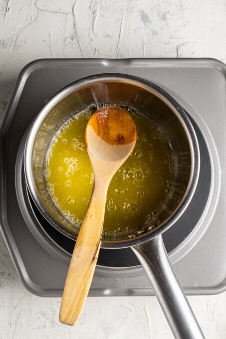 Melted butter in a sauce pan with a wooden spoon in it.