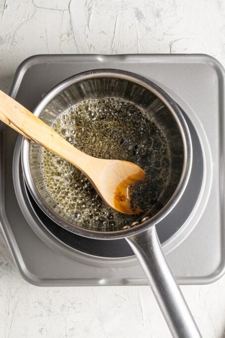 Mint butter sauce in a sauce pan and a wooden spoon in it.