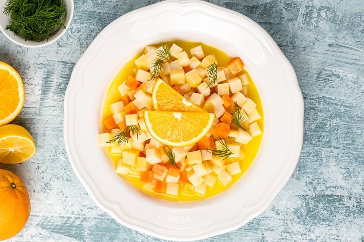 Celeriac vegetable cooked with carrot, quince and citrus flavors served in a white dish.