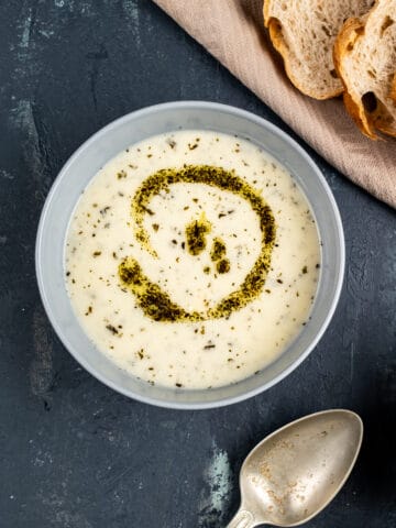 Yogurt soup with rice with a butter mint topping in a grey bowl on a dark background.