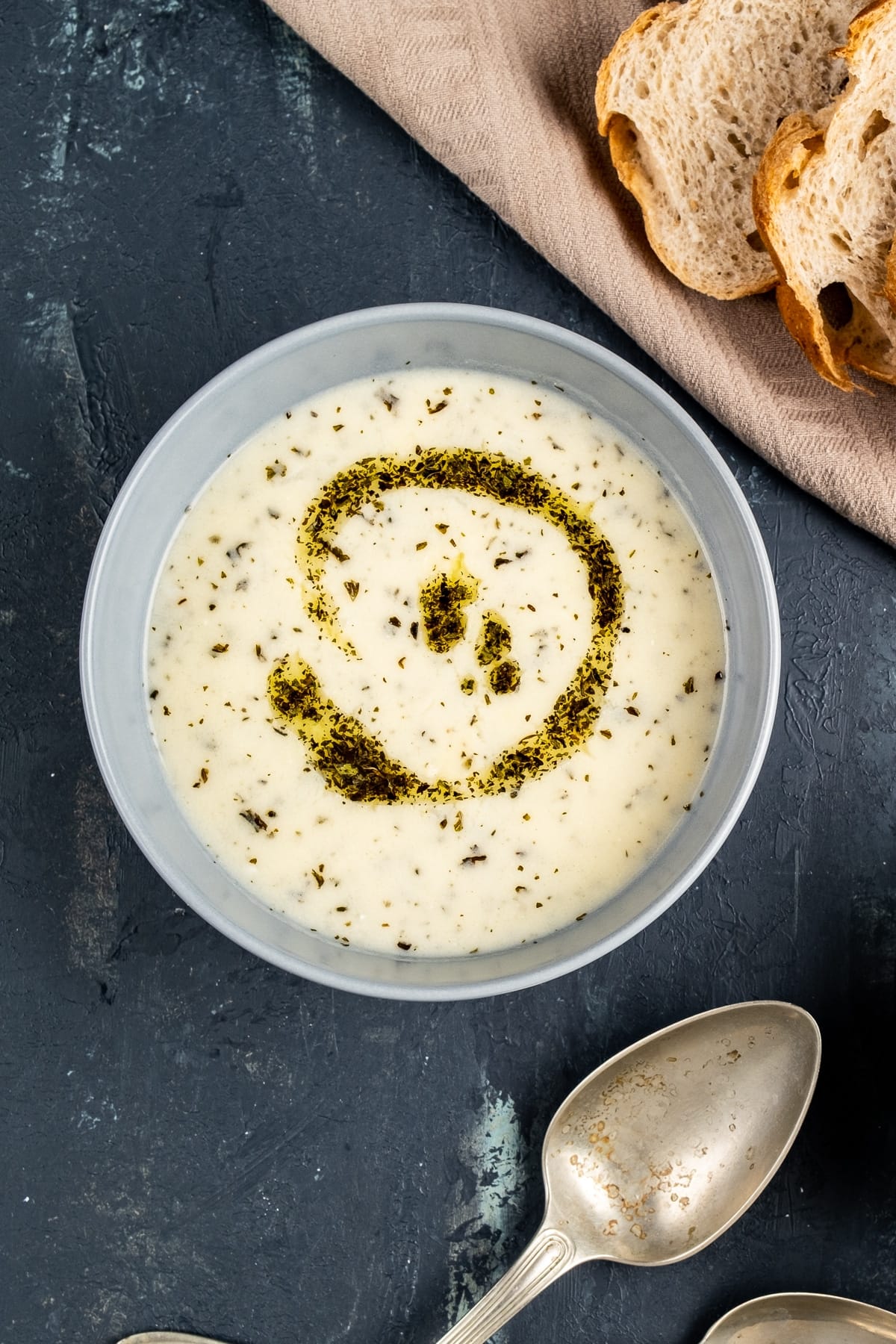 Yogurt soup with rice with a butter mint topping in a grey bowl on a dark background.