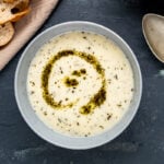 Yogurt soup with mint sauce in a grey bowl on a dark background.