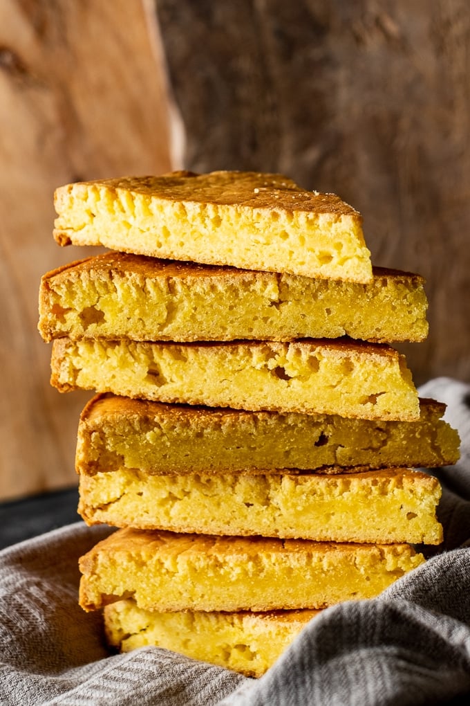 A stack of slices of cornbread made with hot water and wooden boards on the back.