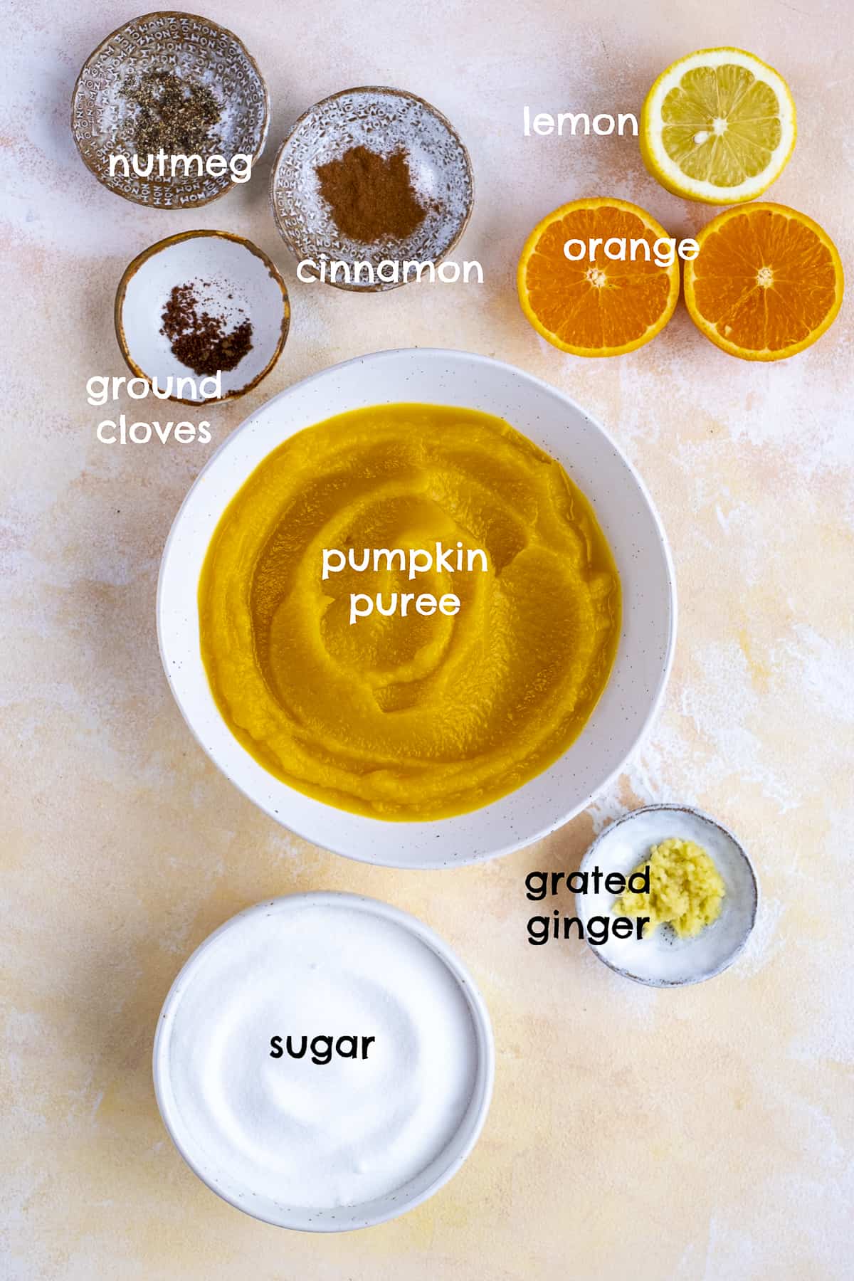 Pumpkin puree, ground cinnamon, nutmeg, cloves, sugar, fresh ginger, orange and lemon on a light background.