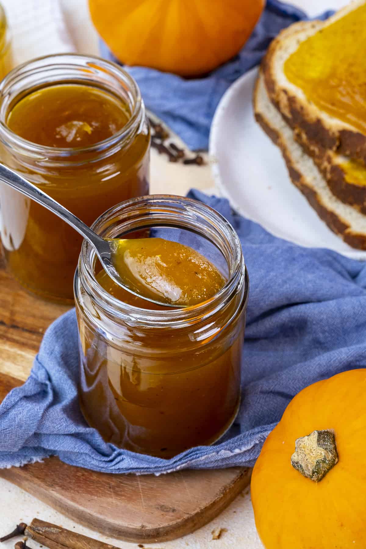 Pumpkin jam in a jar with a spoon inside it, another jar behind it.