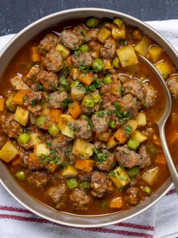 Meatball stew served in a bowl and a spoon inside it.