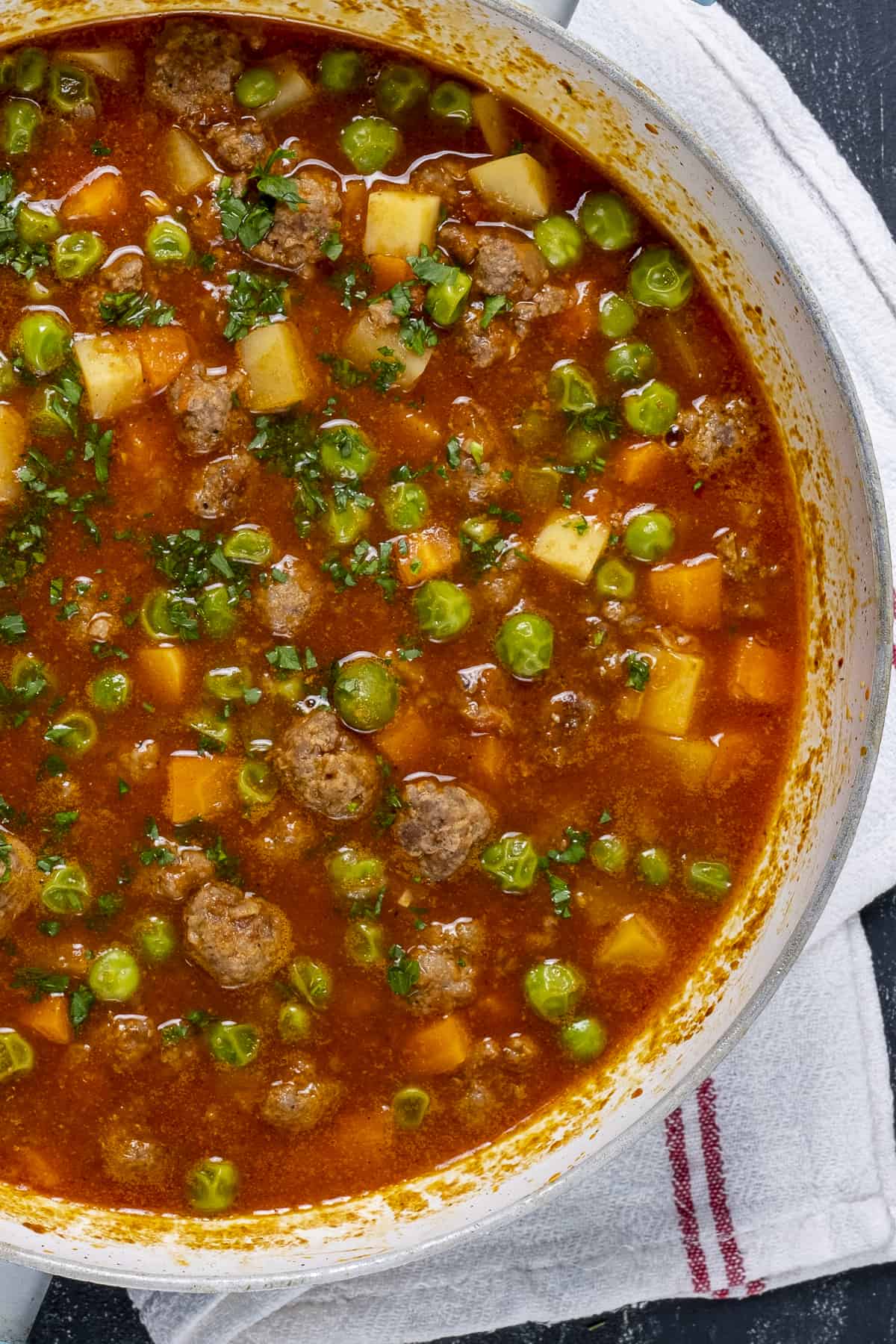 Meatball stew with potatoes, carrots and peas in a pan.