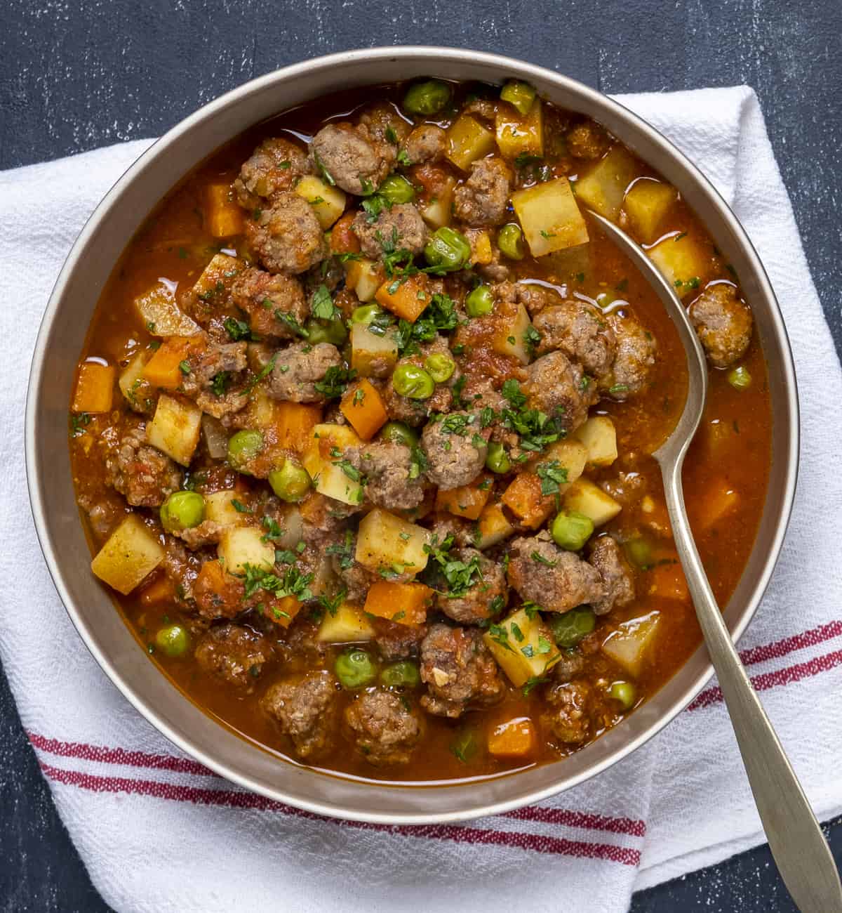 MEatball stew in a bowl and a spoon in it.