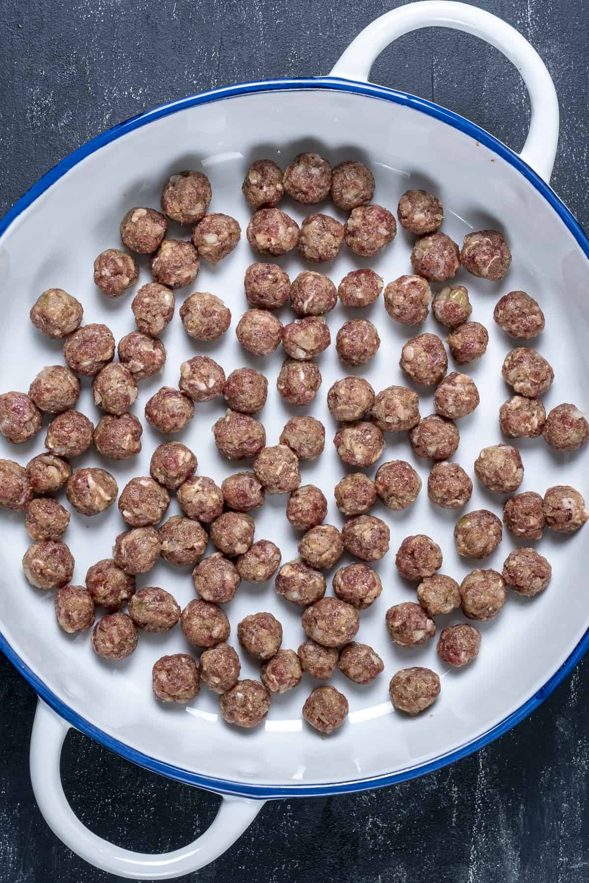 Mini meatballs in a white pan before cooking.