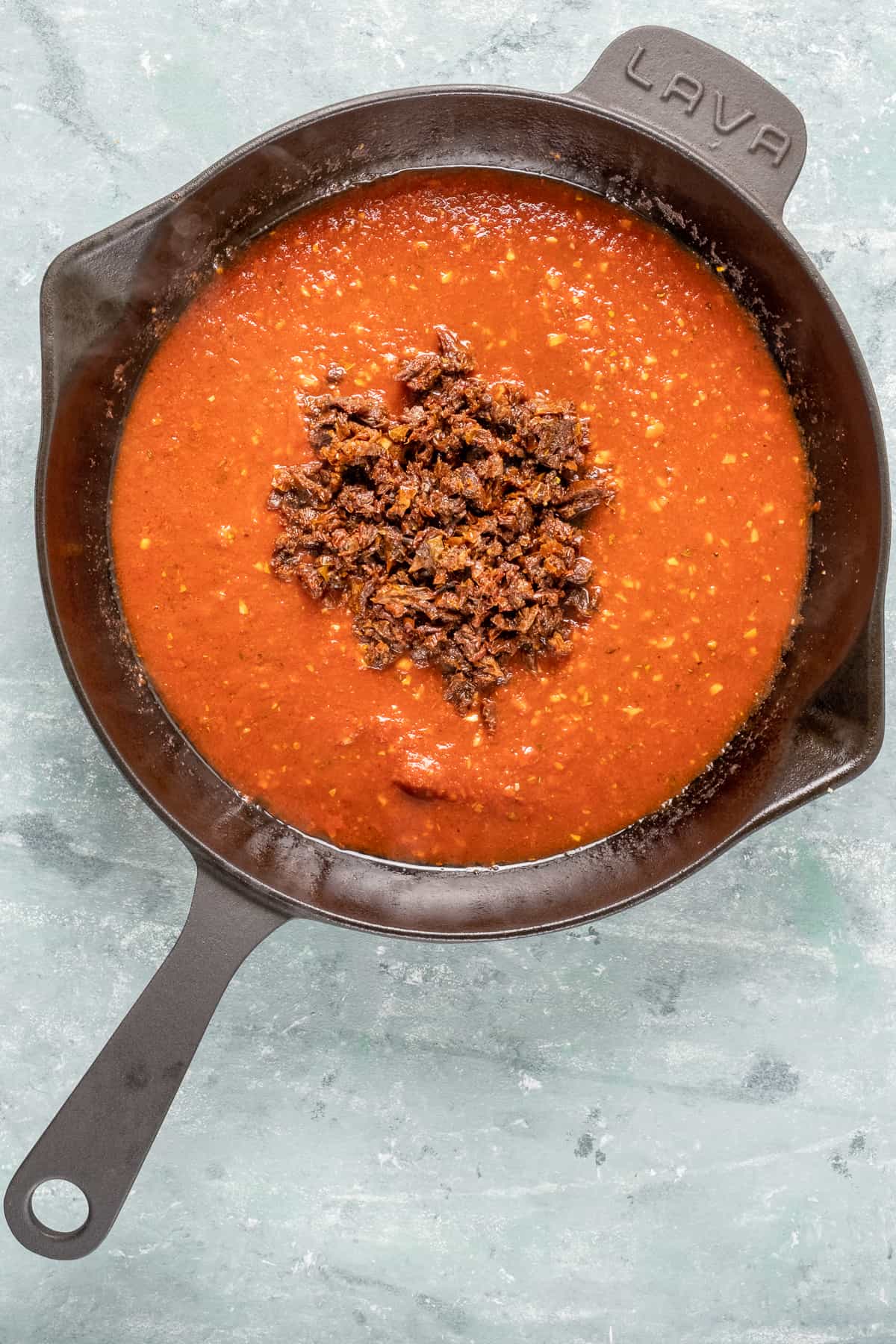 Chopped sun-dried tomatoes in a spicy tomato sauce in a cast iron skillet.