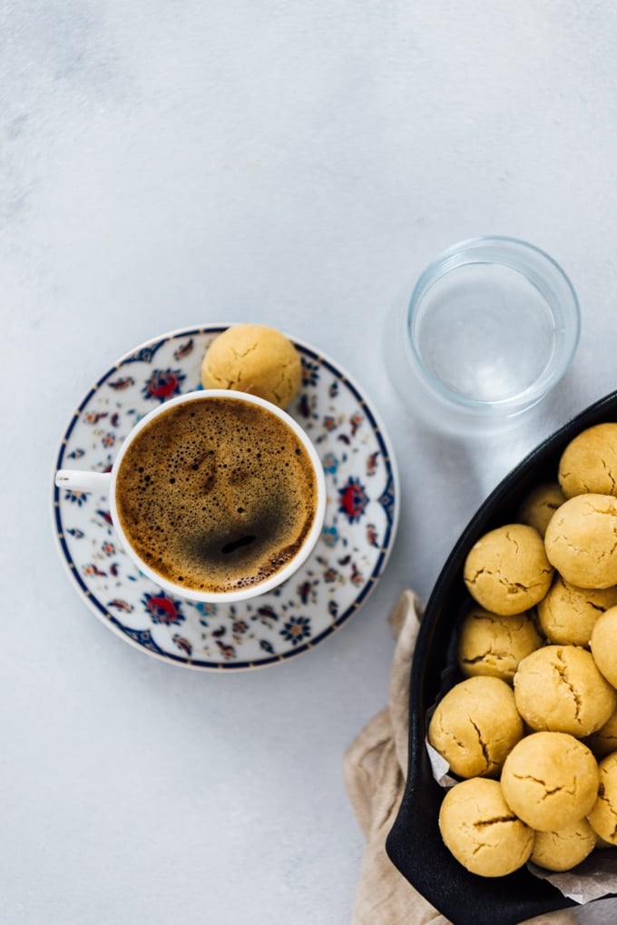Melting-in-your-mouth tahini cookies with 4 ingredients. No eggs or butter! #tahini #cookiesrecipe #tahinicookies #vegancookies #butterlesscookies #egglesscookies A cup of Turkish coffee is served with a tahini cookie on the side.