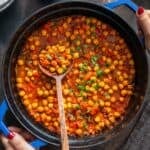 Turkish chickpea stew (Nohut Yemeği) in a blue pot with a wooden spoon, garnished with parsley, and text overlay reading “Nohut Yemegi – Turkish Chickpea Stew.”