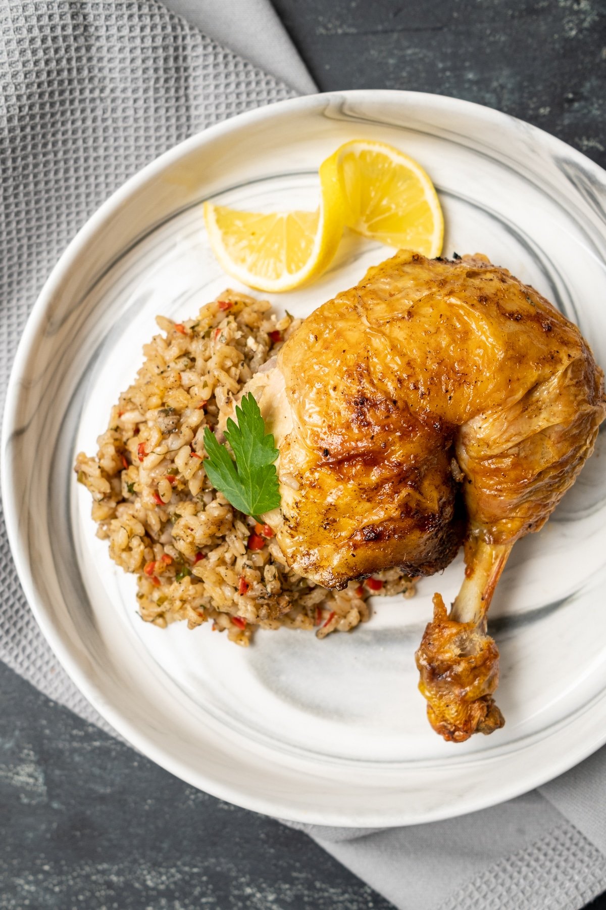 One portion rice stuffed chicken and a lemon slice on a white plate.