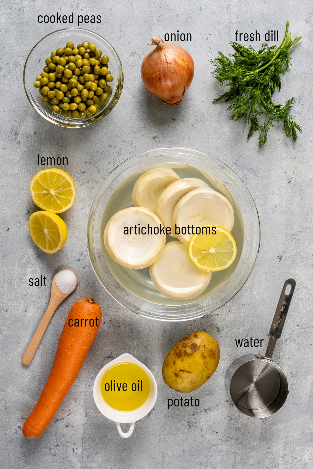 Artichoke bottoms, peas, onion, fresh dill, lemon, carrot, potato and olive oil on a grey background.