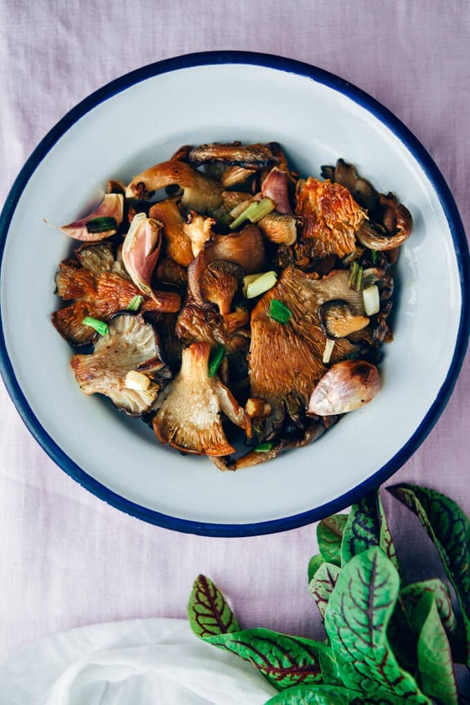 Fried osyter mushrooms with garlic and green onions served in a white bowl