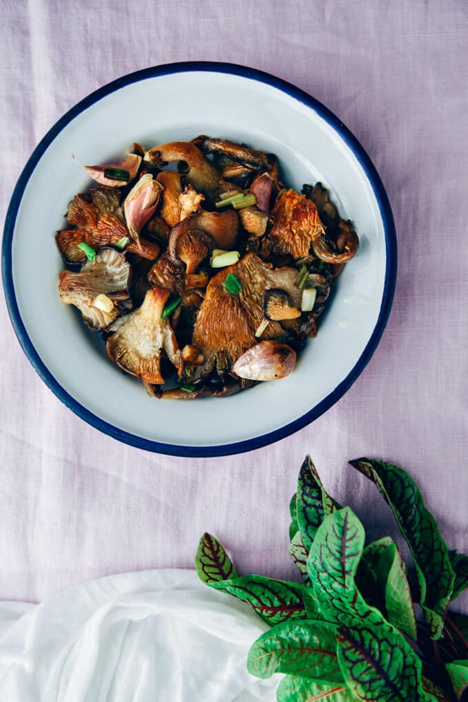 Fried oyster mushrooms with garlic and green onions served in a white bowl