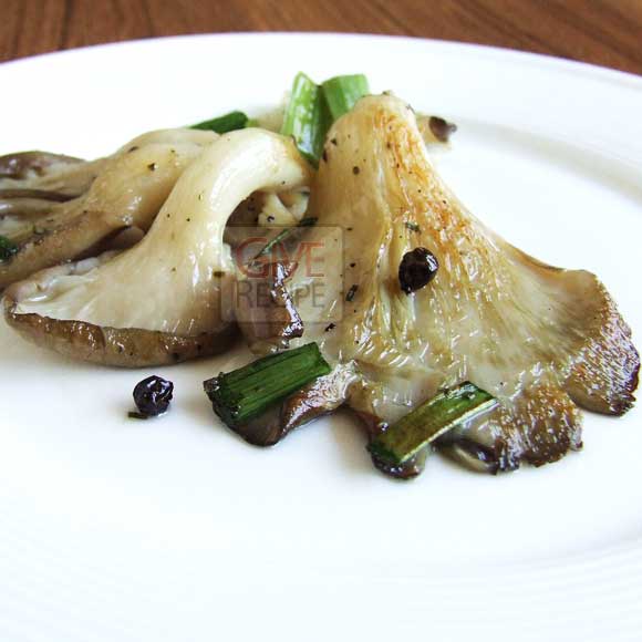 Fried Oyster Mushrooms with herbs and black pepper on a white plate