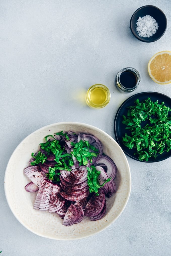 Would you like to take your picnic food to next level?Serve it with sumac onions! #sumac #turkishfood #onionsalad #onionrecipe Sumac onions with parsley in a white bowl