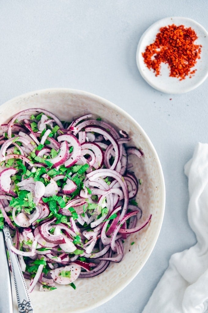 Sumac onions with parsley in a white bowl