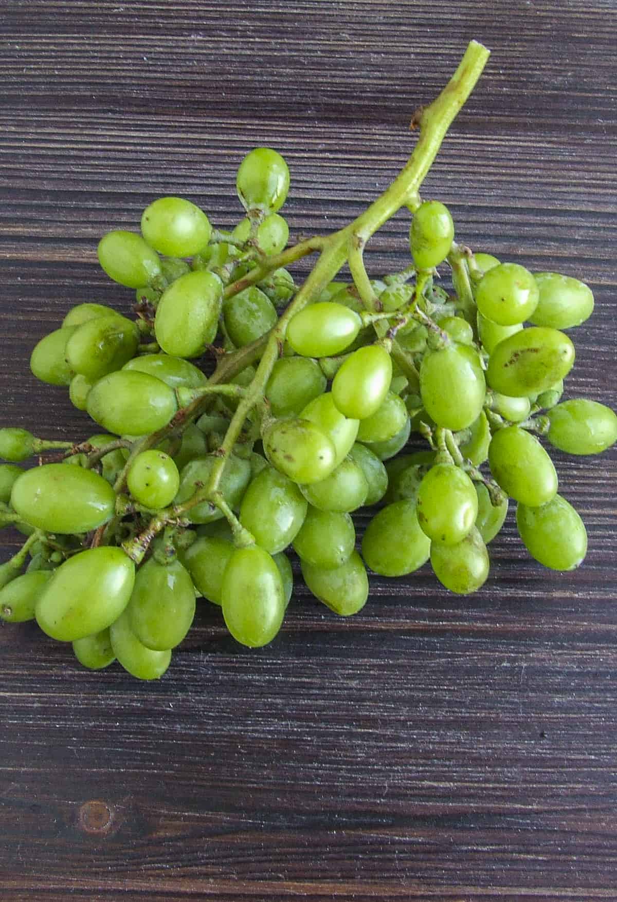 Unripe grapes on a wooden board.