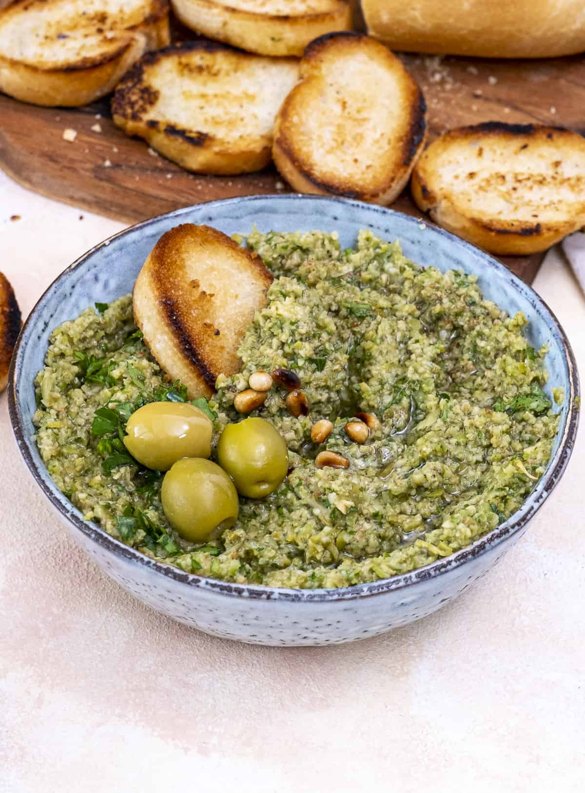 Tapenade garnished with green olives, pine nuts and crostini.