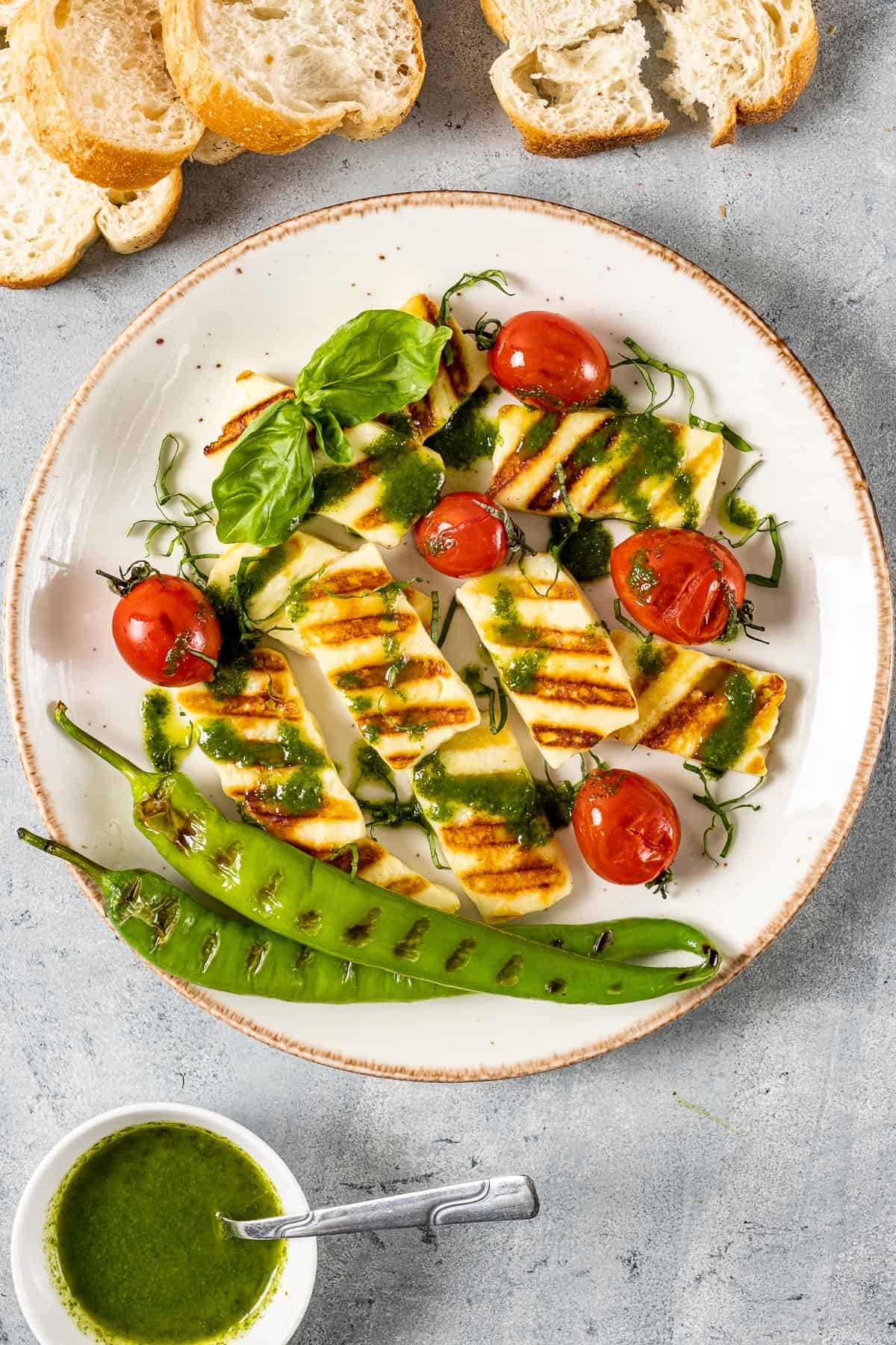 Grilled halloumi served with grilled tomatoes and peppers drizzled with a basil olive oil sauce.