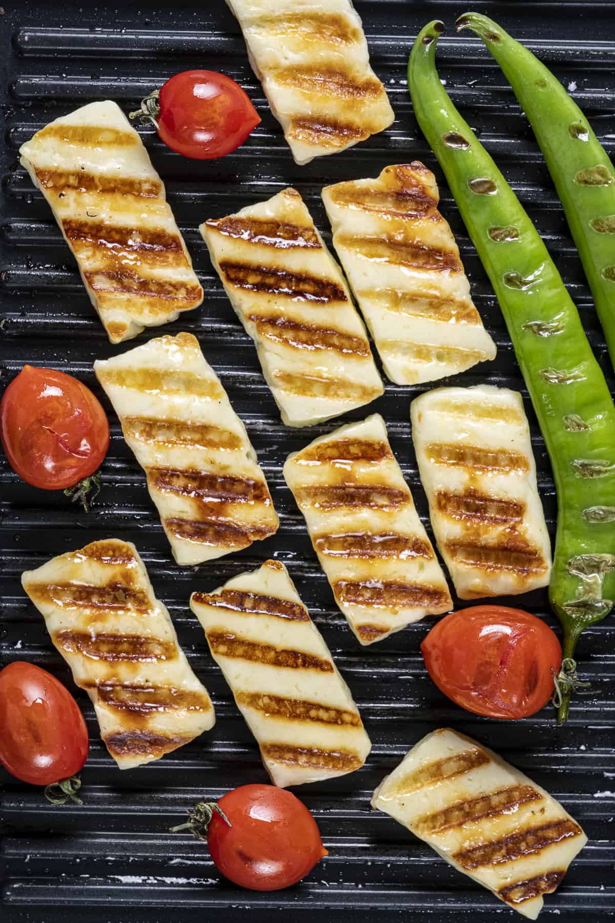Halloumi slices, cherry tomatoes and green peppers on the grill.